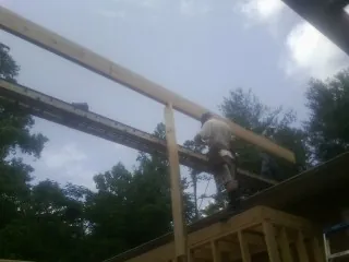 Carpenter setting a ridge beam over a new addition frame — Ice Dam Removal by Roofing Brothers in Roy