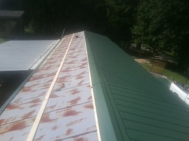 Old rusted panels beside newly installed green metal roofing — Wind Damage Roof Repair by Roofing Brothers in Roy