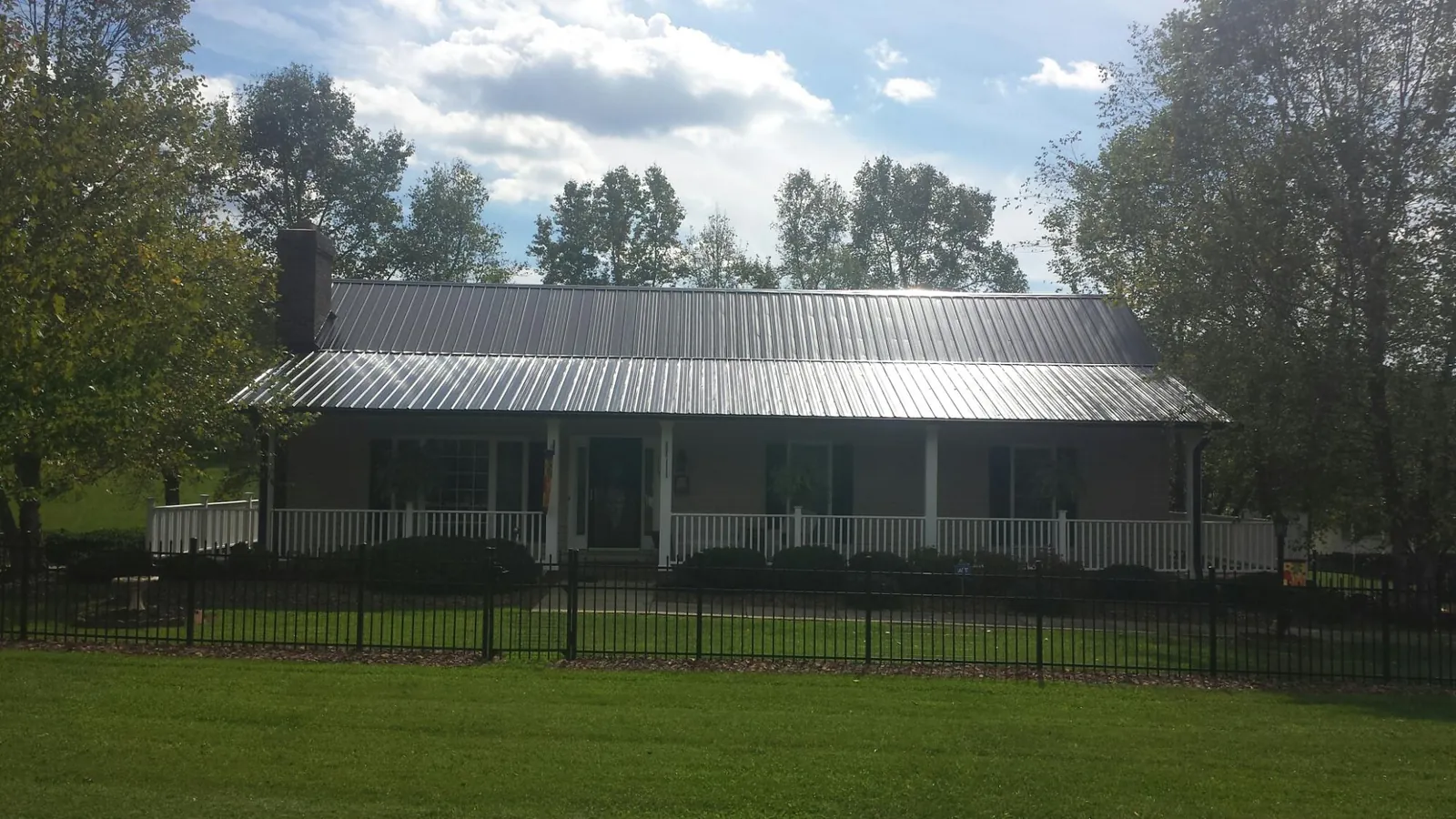Gray metal roof on a brick ranch with a full width front porch — Gutter Guard Installation work by our crew in Roy