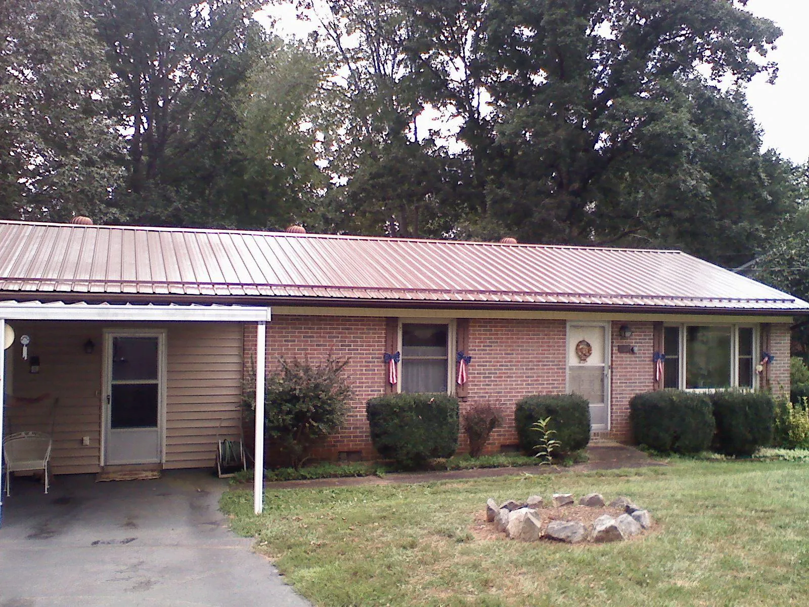 Bronze metal roof and carport on a brick ranch home — Roof Repair work by our crew in Roy