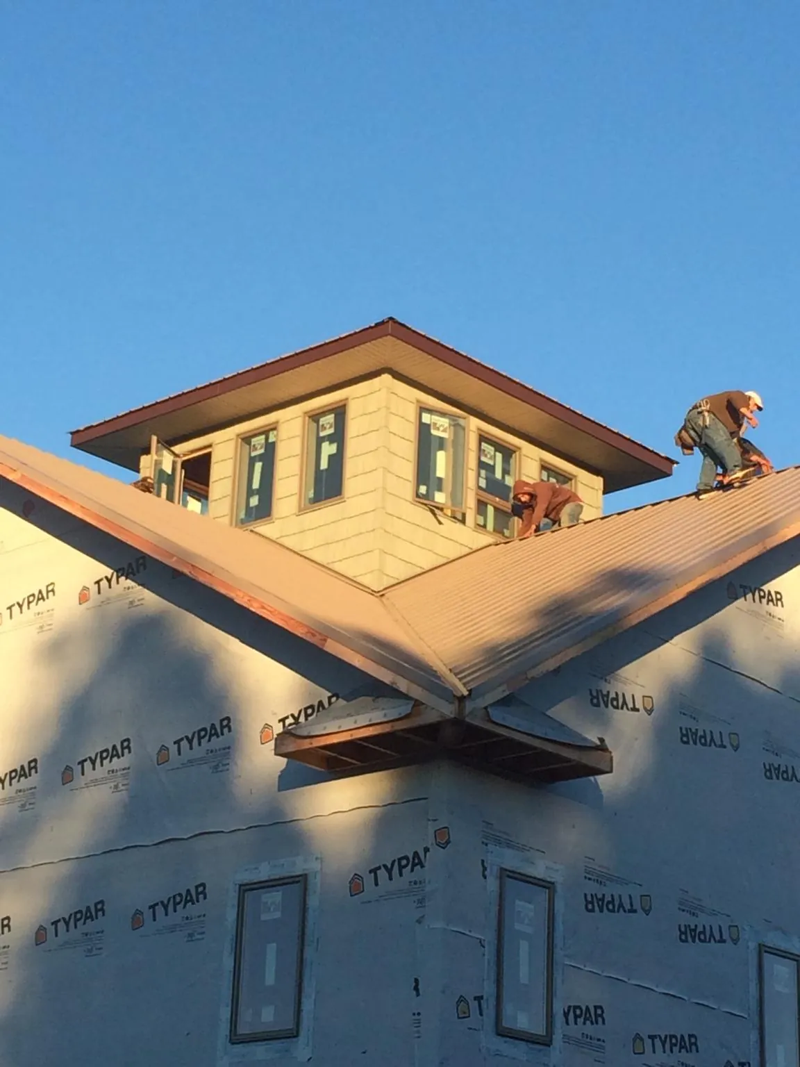Roofers working around a rooftop cupola on a new metal roof at sunset — Roof Waterproofing in Roy by Roofing Brothers
